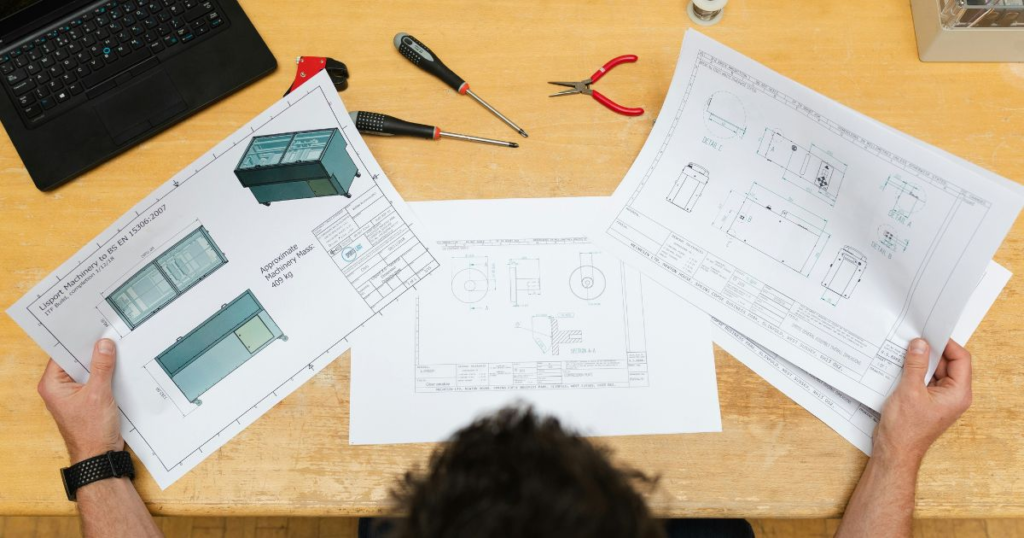 Person examining technical blueprints and tools.
